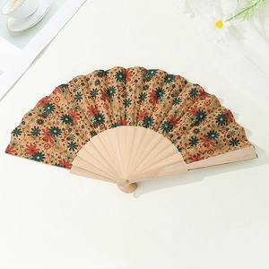 Detailed view of an open cork fan with vibrant floral patterns on a white table