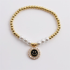 Gold beaded pearl bracelet with a sparkling zircon smiley face charm on white background