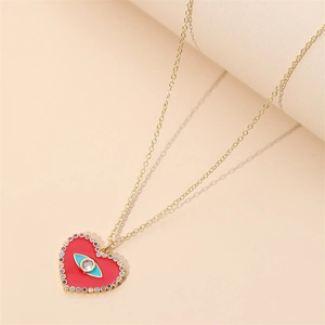 Collier cœur en or avec émail rouge et cristaux sur un fond au style minimaliste