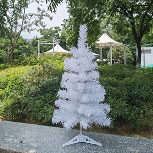 Close-up of white artificial mini Christmas tree with a plastic tripod base outdoors