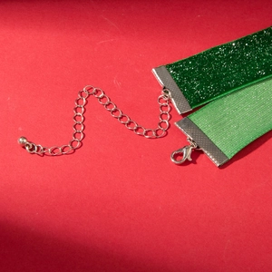 Detail of green velvet and satin collars with silver clasps on a festive red background