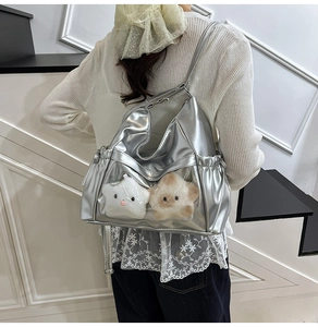 Detail of silver metallic tote bag with clear display pocket and star plush charms