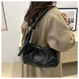 Detailed view of black litchi pattern shoulder bag with a stylish knotted strap design