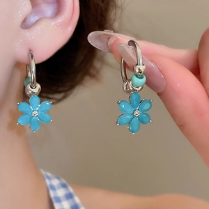 Close-up of blue floral earrings with turquoise beads and small diamond accents