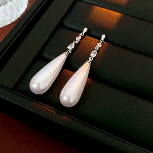 Macro detail of 14k gold plated drop pearl earrings with zircon studded silver chains