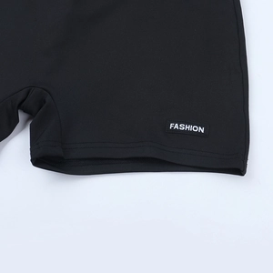 Close-up of black athletic shorts with flat-stitched hem and Fashion woven label