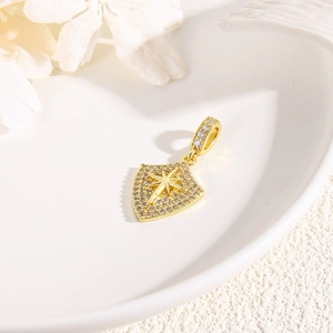 Macro detail of gold shield pendant with sparkling pavé crystals and star engraving