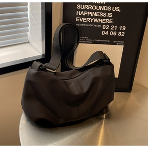 Detail of a black minimalist dumpling bag on a silver table with aesthetic shadows