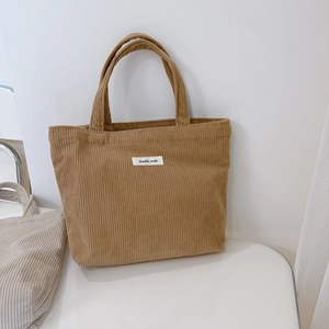 Close-up of camel corduroy tote bag with dual handles and 'simple wish' textile label