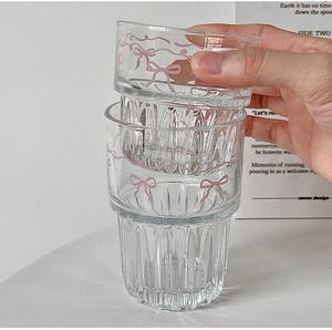 Close-up of stackable glass cup featuring pink bow pattern and ribbed relief texture