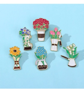 Flat lay of six colorful enamel pins featuring flower bouquets in coffee mugs and cups