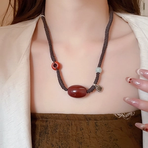 Detailed shot of ethnic wax rope necklace with agate bead and vintage metal pendant