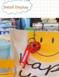 Detail of a soccer keychain with red 'GOOOOOAL' strap hanging on a white canvas bag