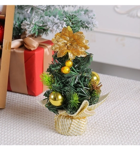 Close-up of a mini Christmas tree with gold flower, ornaments, and burlap base