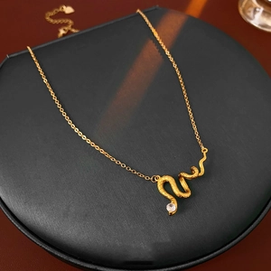 Detail of gold snake pendant with textured scales and sparkling round cubic zirconia stone