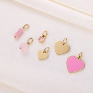 Detailed view of pink crystal, enamel, and gold heart-shaped pendants on soft silk