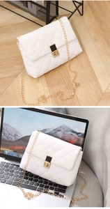 Detail of white quilted crossbody bag with golden chain and black-gold lock on laptop