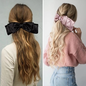 Detail showing oversized satin bow hair clips in black and pink on a female model