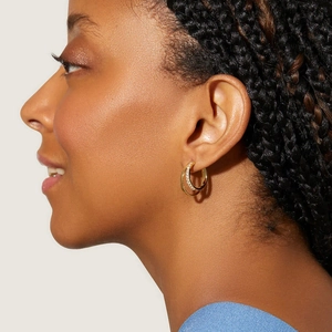Close-up of model wearing 18K gold-plated C-shaped earrings with embedded crystals