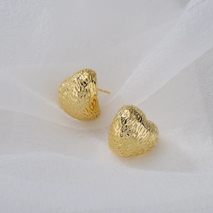 Vintage gold heart studs with bark texture on soft white gauze background