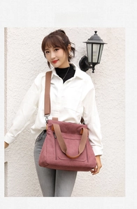 Detail of burgundy canvas tote bag with adjustable shoulder strap and zip front pocket