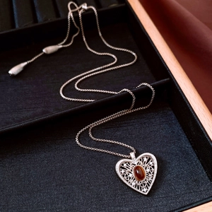 Detail of vintage silver heart necklace with amber gemstone in a black jewelry box