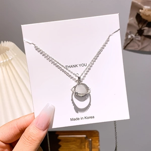 Close-up of silver planet pendant with cat eye stone and diamonds on gift card