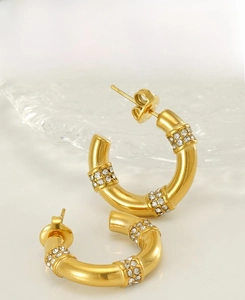Macro view of gold bamboo-shaped hoop earrings with sparkling cubic zirconia inlay