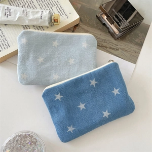 Detailed view of denim coin purses with star patterns and silver zippers in two shades of blue