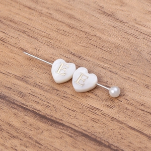 Détail du pendentif cœur en nacre avec lettre E dorée et perle sur épingle en métal