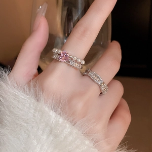 Détail de bagues avec cœur rose en zircon et perles portées par un mannequin