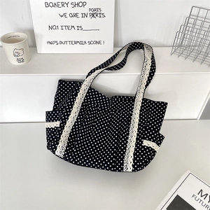 Detail of black polka dot canvas tote bag featuring delicate white lace trim and straps