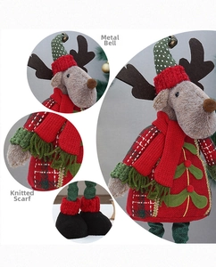 Detail view of plush Christmas reindeer doll with knitted scarf and metal bell charm