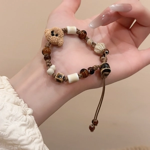 Close-up of a brown woven ceramic beaded bracelet with a cute resin bear charm