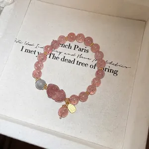 Detailed macro view of strawberry quartz beads and a carved pixiu charm on the bracelet