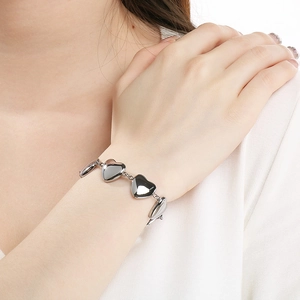 Détail d'un bracelet à maillons en forme de cœur argenté porté au poignet d'une femme