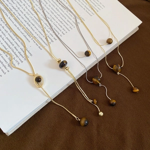 Detail of four retro tiger eye stone necklaces displayed on a vintage book
