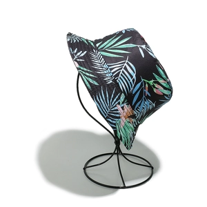Close-up of tropical palm leaf print bucket hat on a display stand with black and green tones
