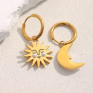 Detail of asymmetric 18K gold plated sun and moon earrings with pearl accents