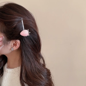 Detail showing the pink strawberry hair clip worn by a model to display the fit and style