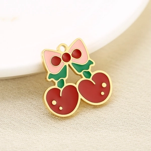 Macro shot of 18K gold plated cherry pendant with red enamel and bow tie detail