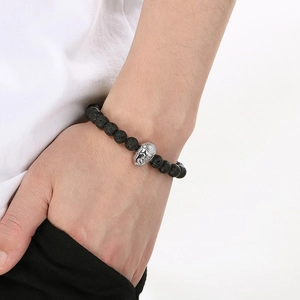 Close-up of 8mm black lava stone bead bracelet with silver Buddha head charm on male wrist