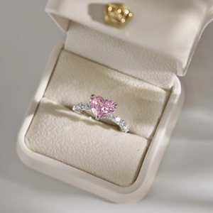Macro detail of a pink heart-shaped stone ring in a white gift box with crown logo
