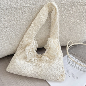 Close-up of floral daisy lace embroidery and ruffled edges on a beige canvas tote bag
