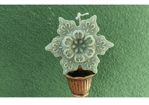 Detail of 3D snowflake scented candle in light green with fine embossed patterns
