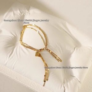 Macro shot of gold-plated triple-layer chain bracelet with tassel fringe and square charm
