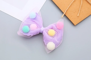 Detailed close-up of a purple mesh hair bow filled with colorful mini plush pompoms
