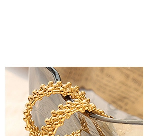 Macro shot of 18k gold plated titanium hoop earrings with textured woven detail on paper