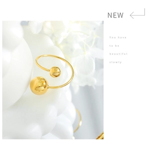 Détail d'une bague bypass dorée minimaliste avec deux sphères métalliques polies