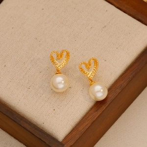 Elegant hollow heart earrings with pearl drops on vintage textured wooden display